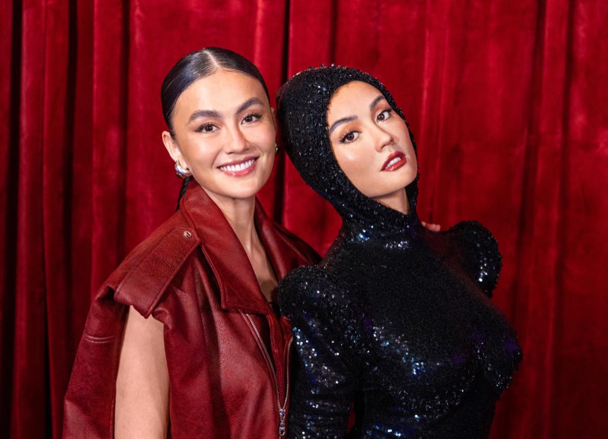 Agnez Mo poses cheek to cheek with her wax figure, which wears a black sequined hooded jumpsuit