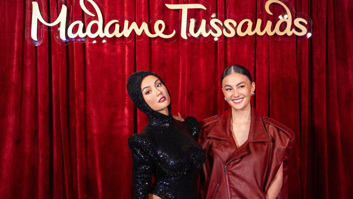 Singer Agnez Mo stands beside her new wax figure under the Madame Tussauds sign at Madame Tussauds Hollywood