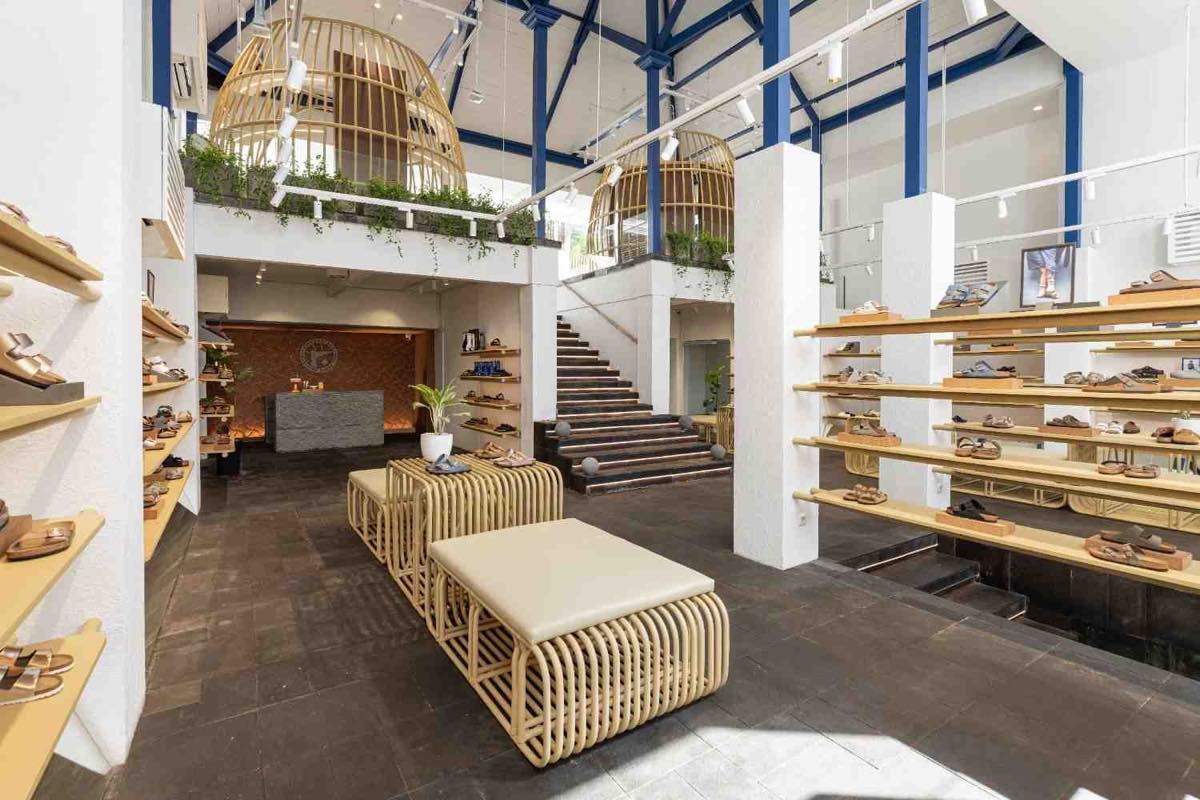 Inside BIRKENSTOCK Umah Ubud, a two-storey space with rattan cage lighting, woven benches and open shelving of sandals