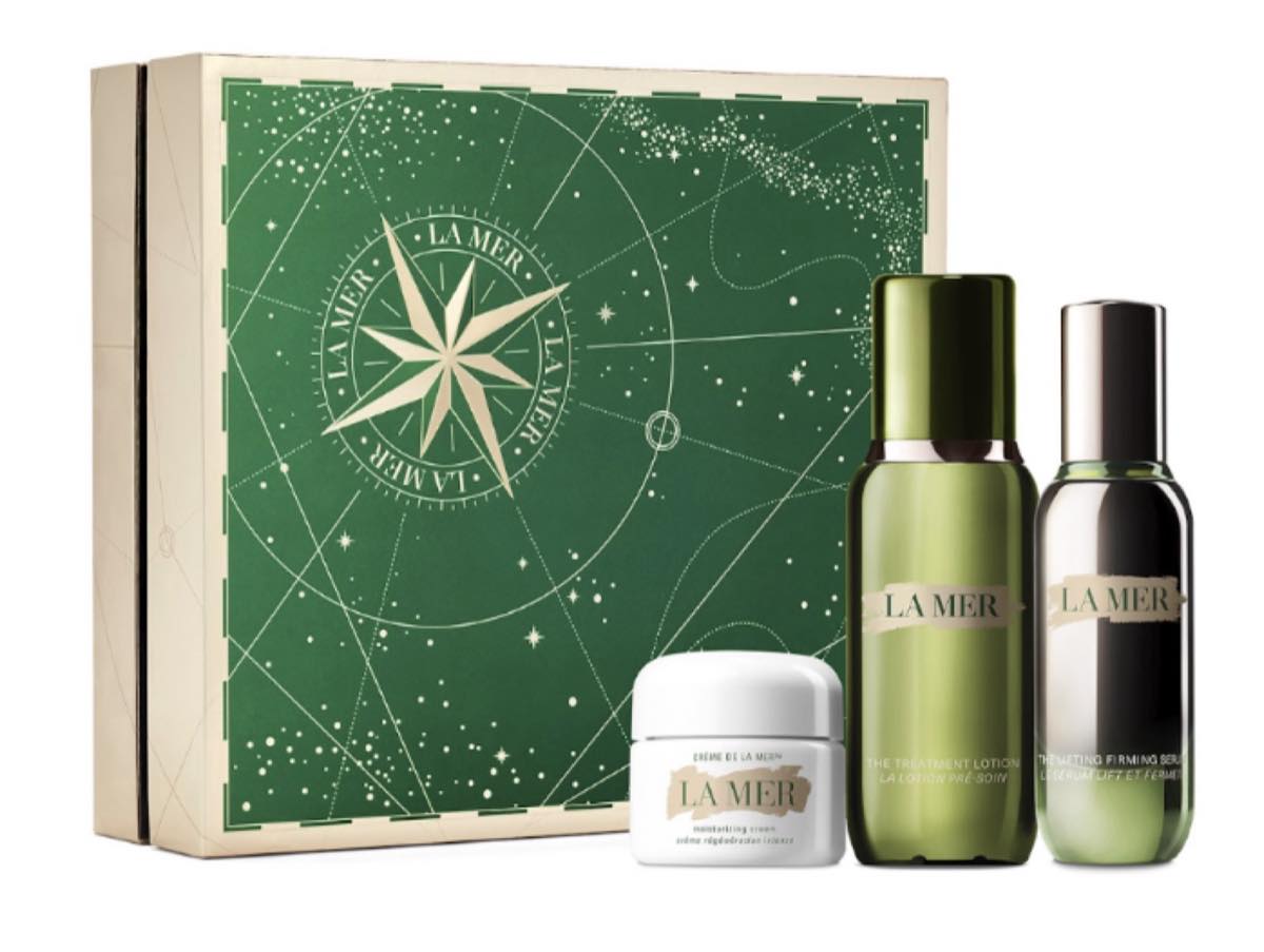 La Mer The Lifting Hydration Collection with Crème de la Mer, The Treatment Lotion and The Lifting Firming Serum beside a green festive gift box