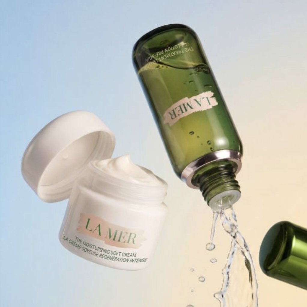 La Mer The Treatment Lotion pouring beside the open Moisturizing Soft Cream jar