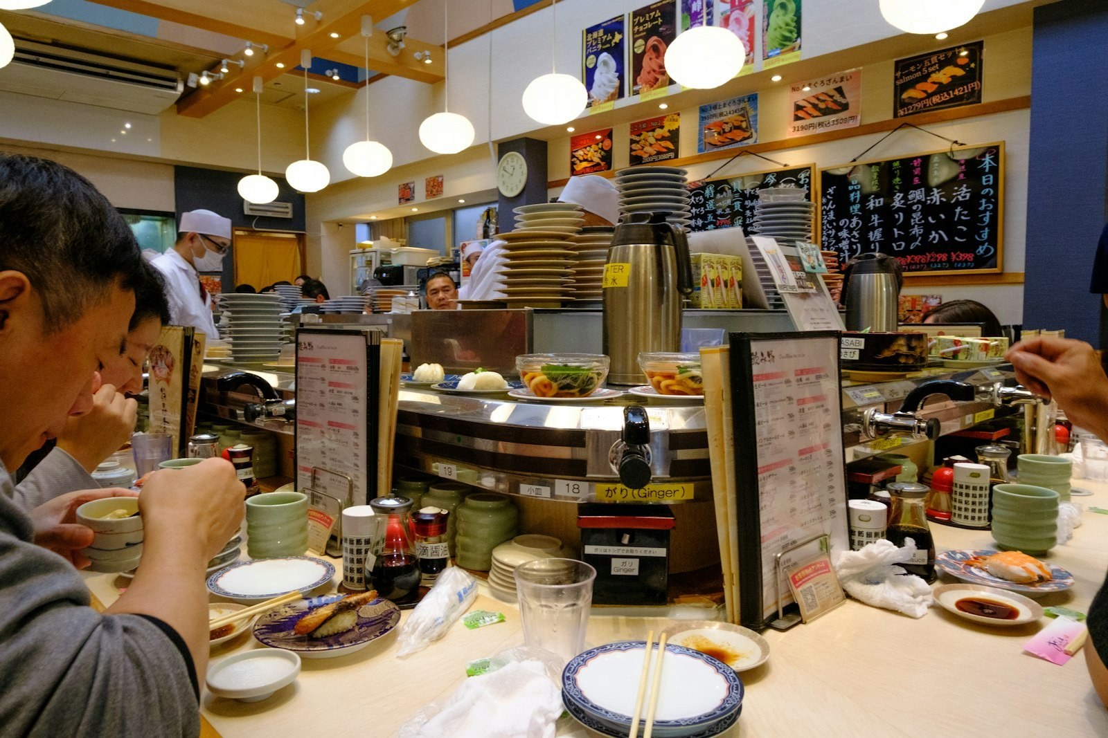 Diners enjoying conveyor-belt sushi at a busy restaurant counter